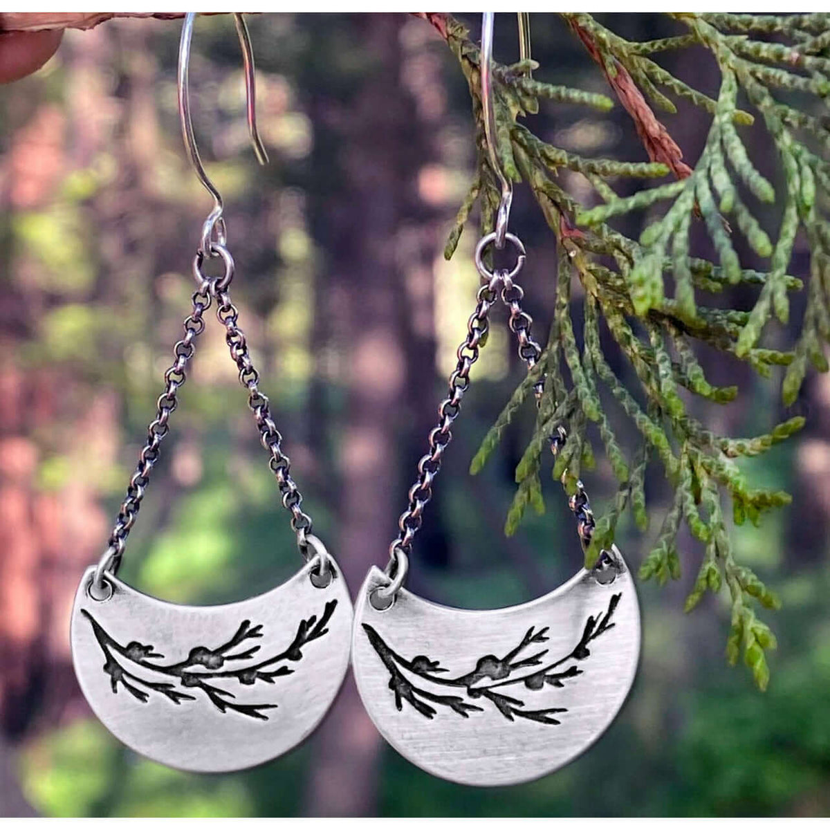 Juniper Earrings -Flowery Branch Nature dangle earrings showcasing silver juniper design against natural background.