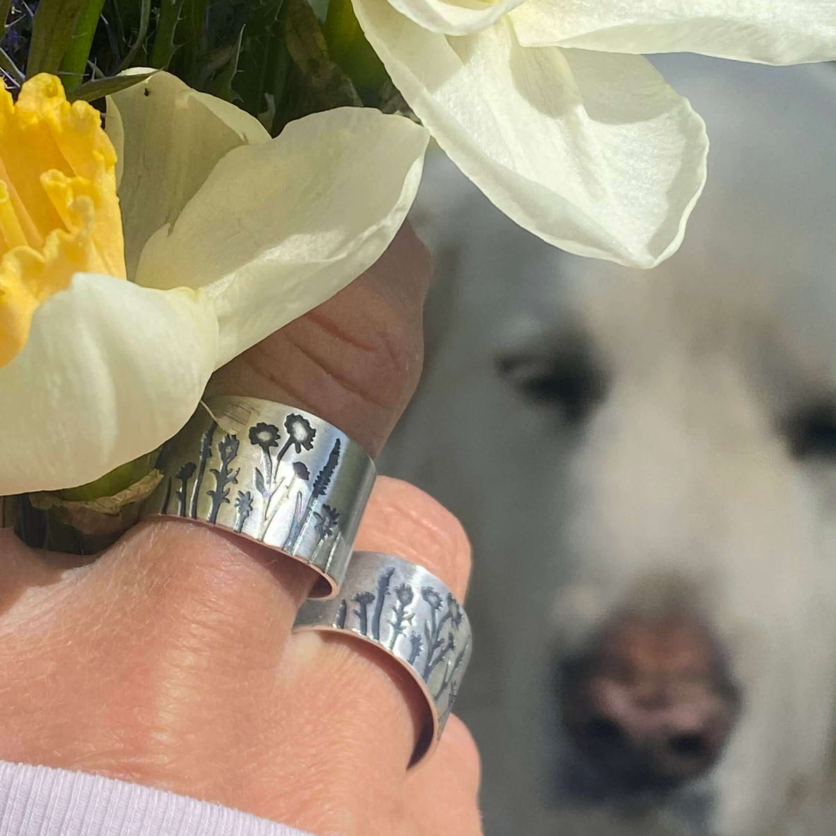 Wildflowers Adjustable Ring displayed with fresh flowers in hand and a soft-focus background of a dog.