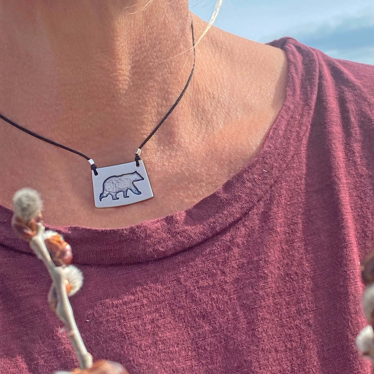 Bear Boy Necklace showcased on a model, featuring a black bear design on an asymmetrical rectangle chain.