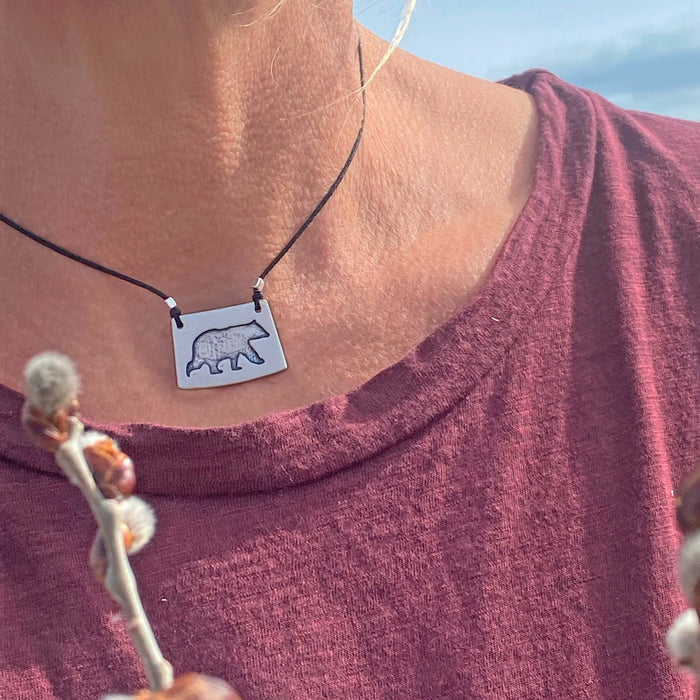 Bear Boy Necklace showcased on a model, featuring a black bear design on an asymmetrical rectangle chain.