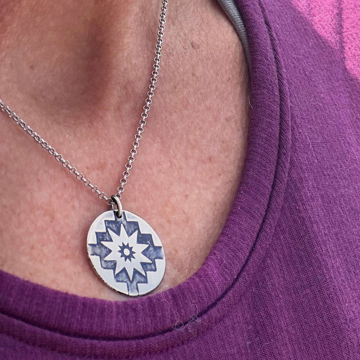 Northstar Necklace worn on a person's neck, showcasing the silver star pendant against a purple shirt.