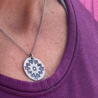 Northstar Necklace worn on a person's neck, showcasing the silver star pendant against a purple shirt.