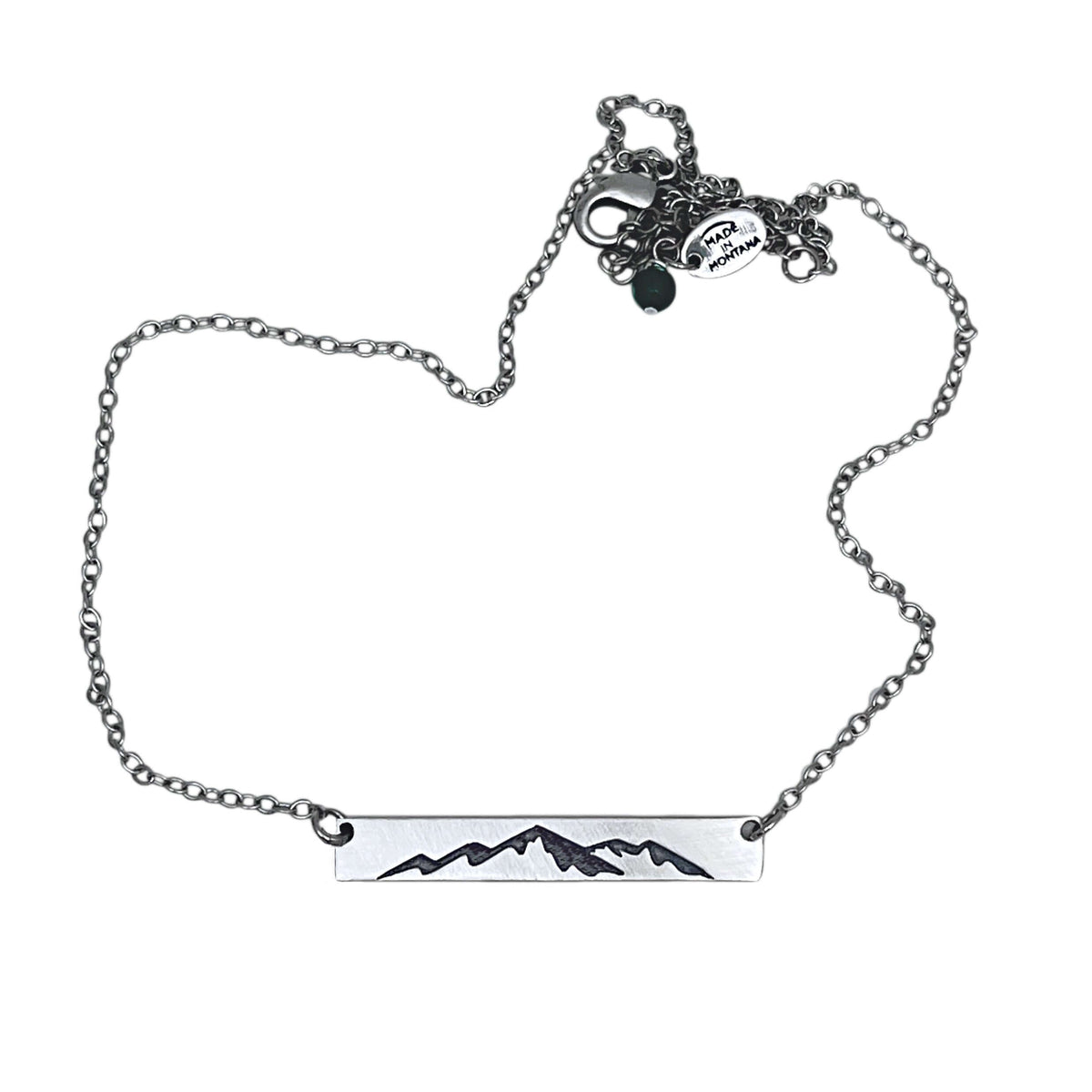Mountainscape Necklace featuring a mountain silhouette etched on a raw brass bar with an adjustable cable chain.