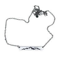 Mountainscape Necklace featuring a mountain silhouette etched on a raw brass bar with an adjustable cable chain.