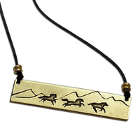 Wild Horses Necklace featuring brass engraving of galloping mustangs against mountain backdrop.