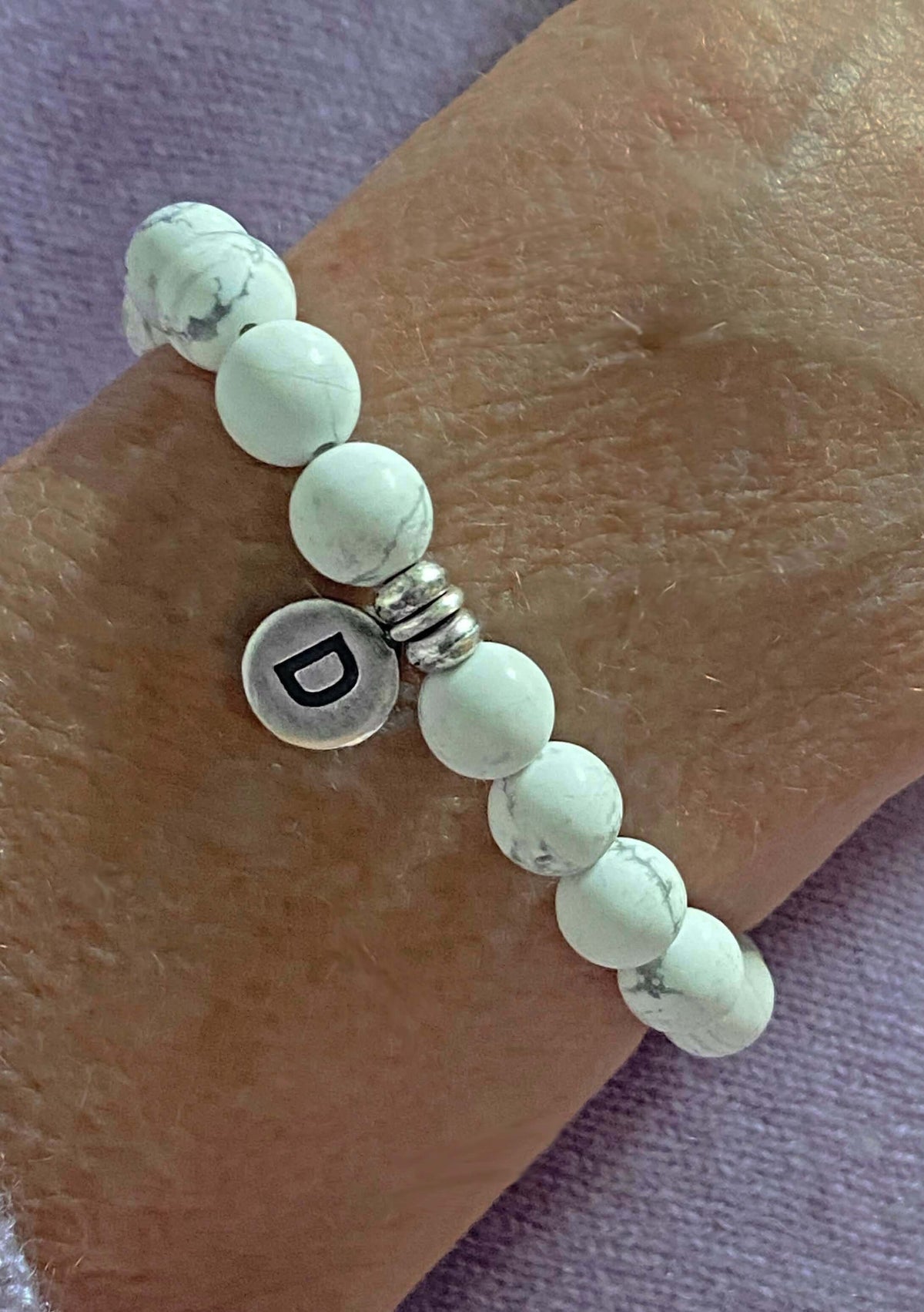 Initial Stretch Bracelet Collection featuring a personalized white Howlite bracelet with a silver initial disk 'D'.