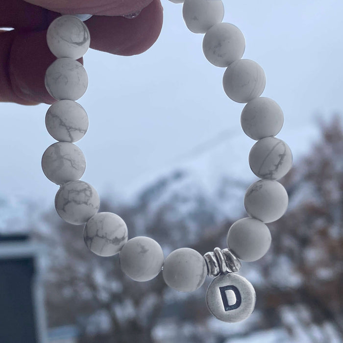 Initial Stretch Bracelet Collection featuring a personalized white Howlite bracelet with initial 'D' charm.