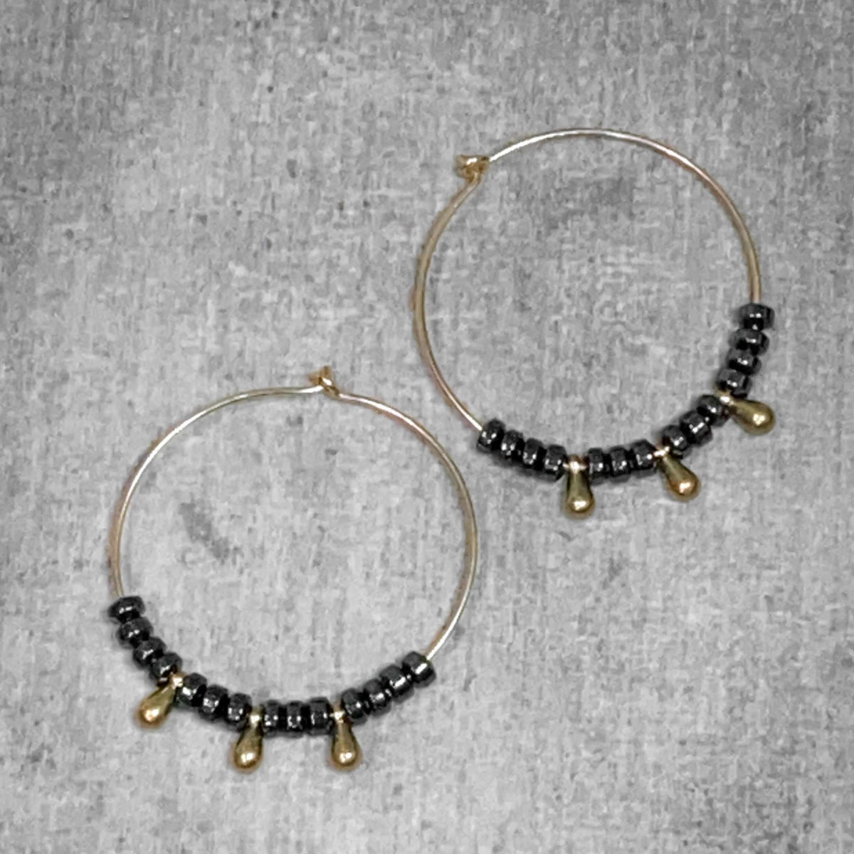 Dew Drops Earrings featuring elegant hematite and beaded hoop design in Matte Silver and Antique Brass finishes.