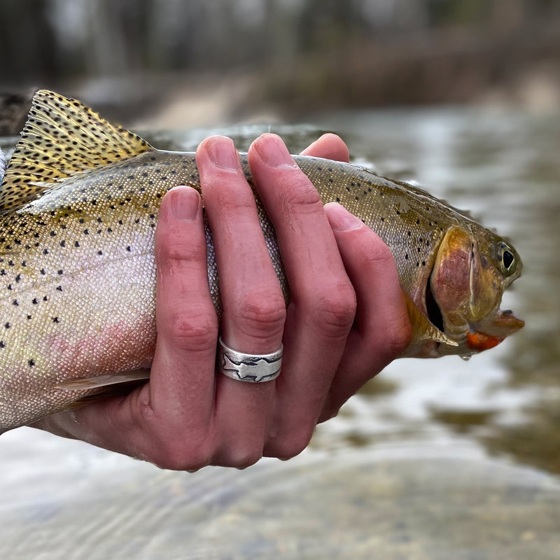 girl holding a trout fish while wearing a trout ring on her finger 