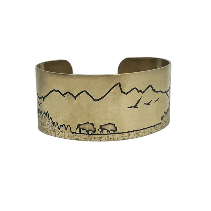 a brass cuff with a mountain scene on it