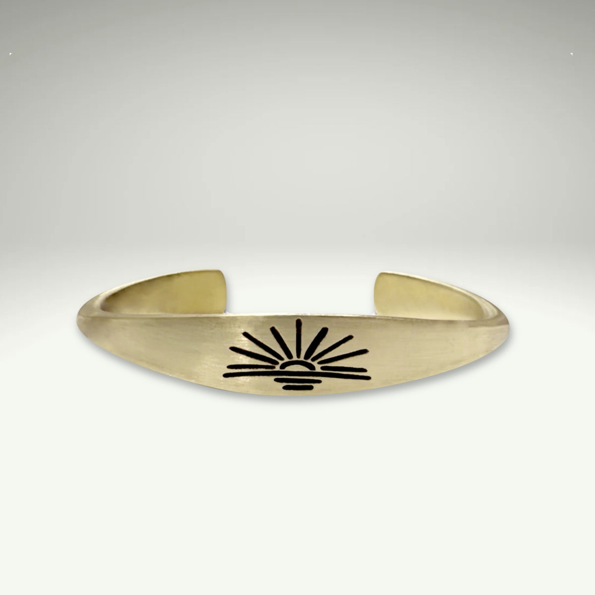 a gold cuff with a sun design on it