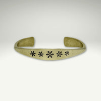 a brass bracelet with black flowers on it