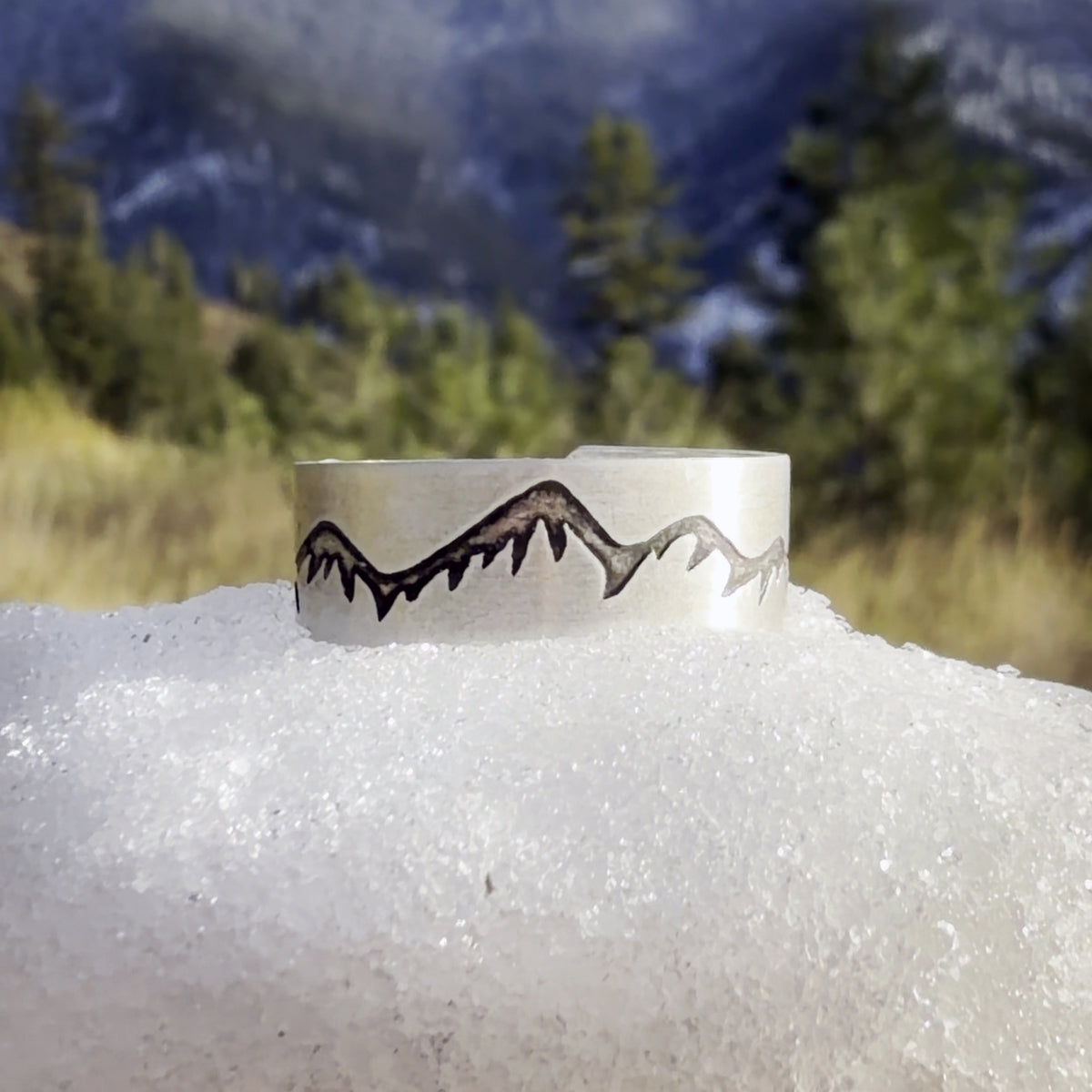 Snowcaps Adjustable Ring in matte silver set in snow with pine trees behind