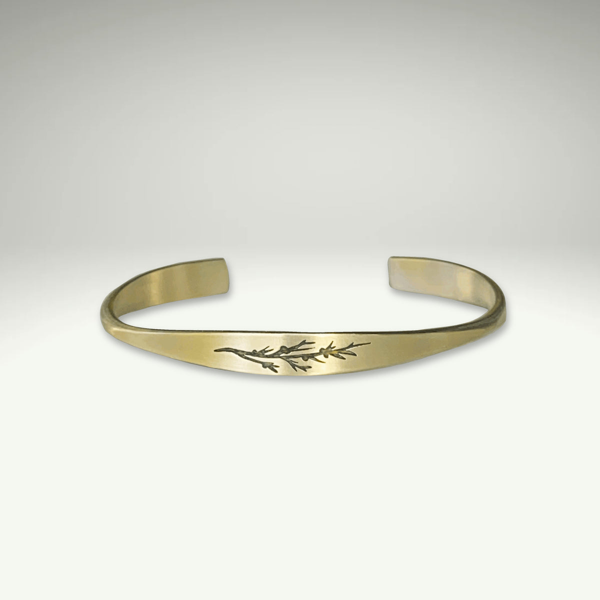 a gold bracelet with a leaf design on it