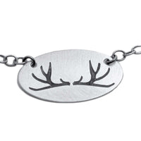 Antlers Necklace featuring etched antlers design on an elegant oval pendant in Matte Silver finish.