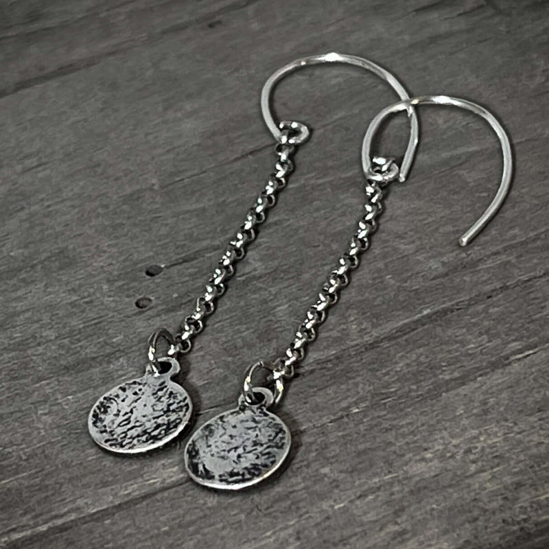Asteroids Earrings featuring textured raw brass disks and oxidized rolo chain, perfect for any accessory collection.