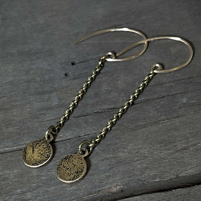 Asteroids Earrings featuring raw brass round disks with a textured design and oxidized rolo chain.