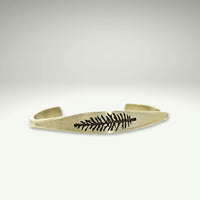 a gold bracelet with a fern design on it