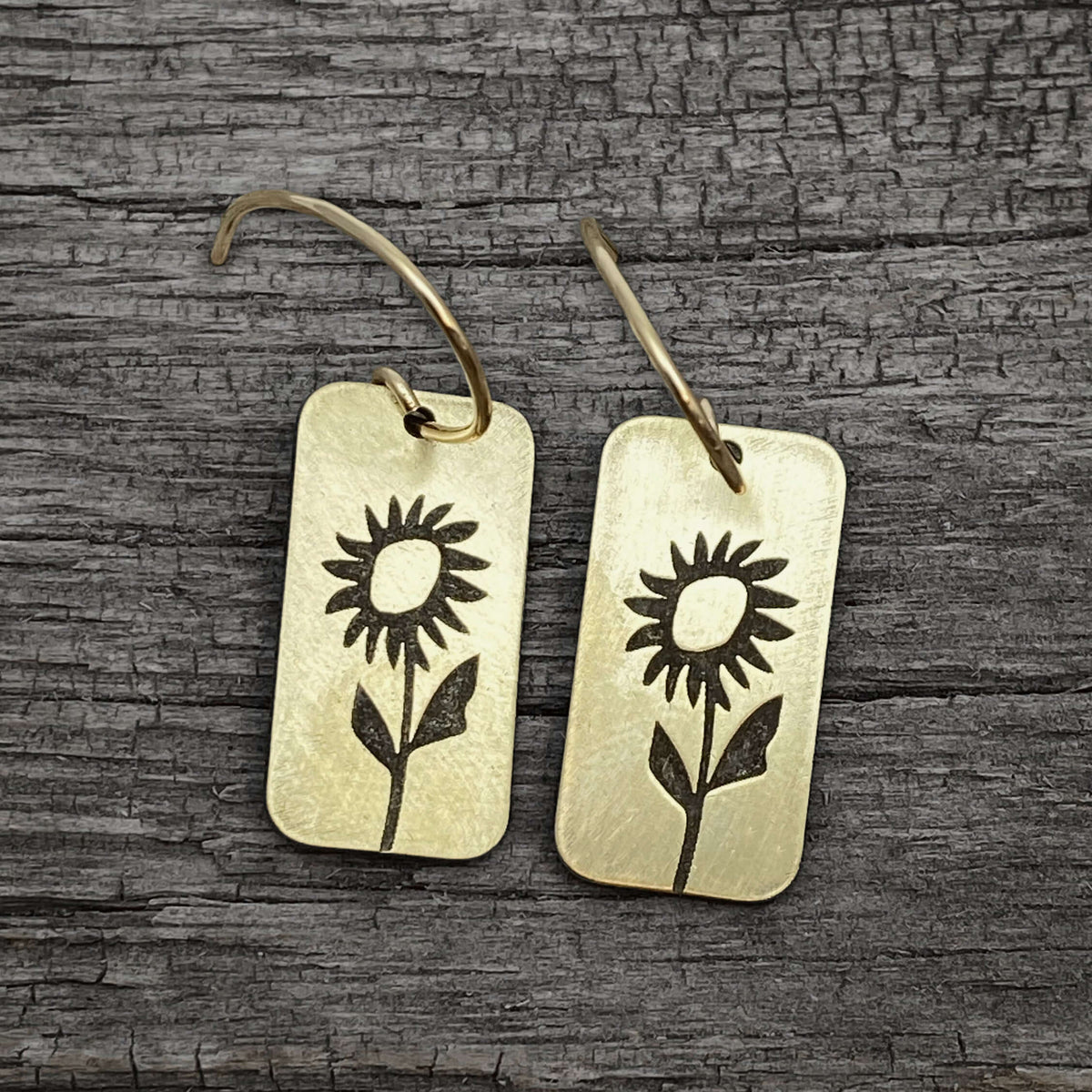 Balsamroot Flower Earrings in antique brass with sunflower design on reclaimed wood background.
