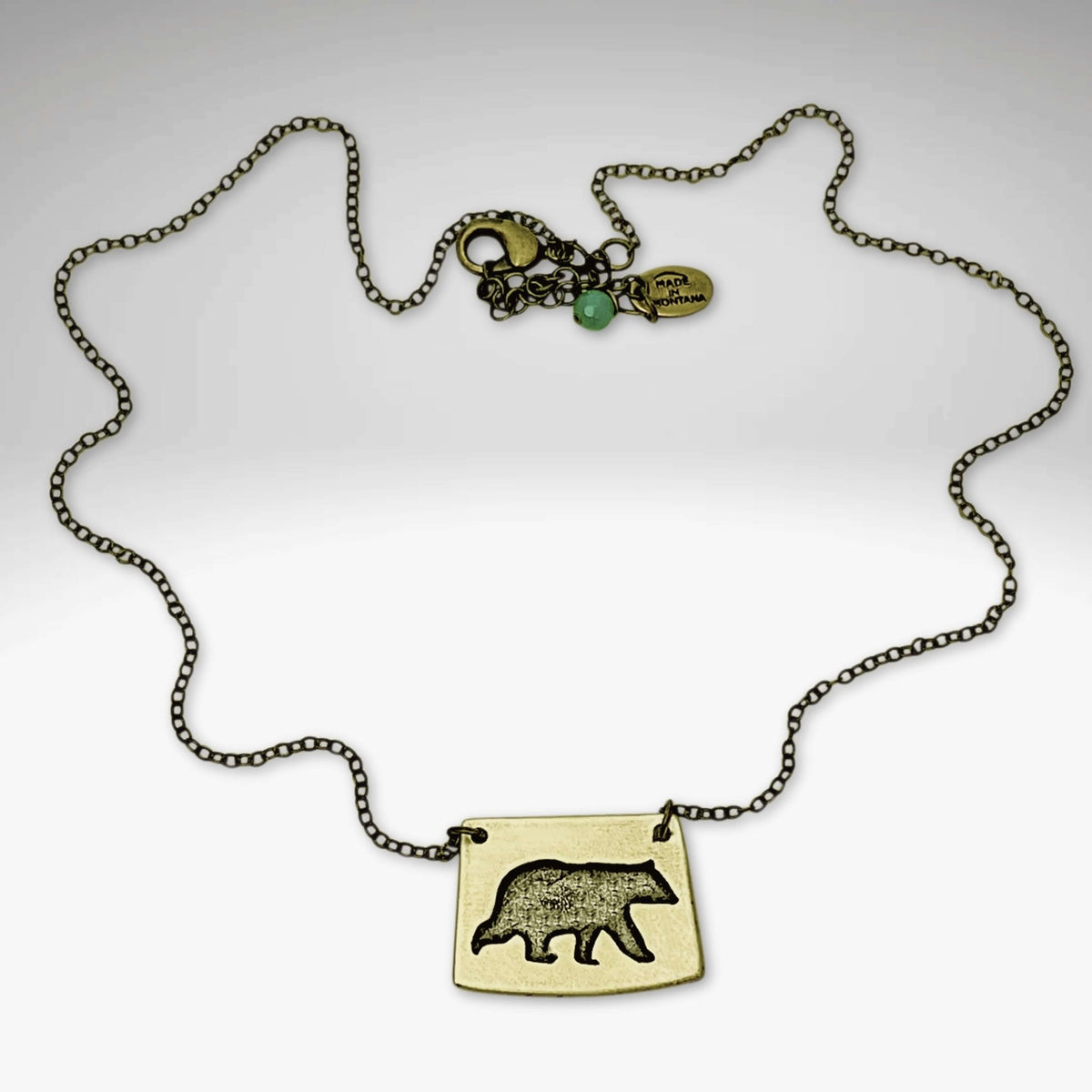 Bear Boy Necklace featuring a black bear charm on an asymmetrical rectangle pendant with a stylish chain.