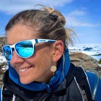Woman wearing Billy Goat Earrings and sunglasses outdoors, showcasing a unique style with a winter backdrop.