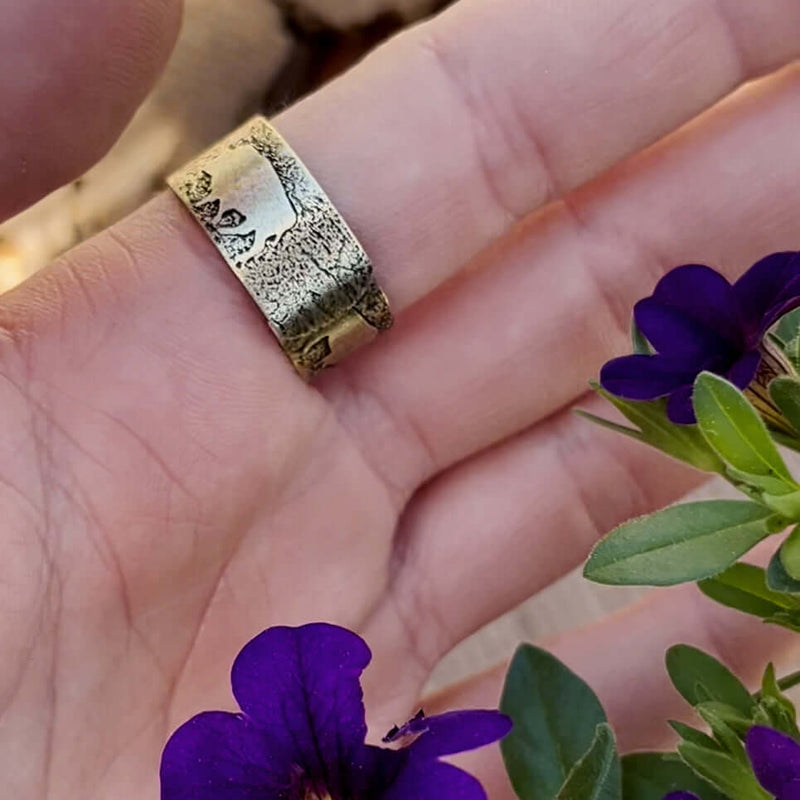 Bison Circles Adjustable Ring shown on a hand with purple flowers, featuring a unique bison motif.