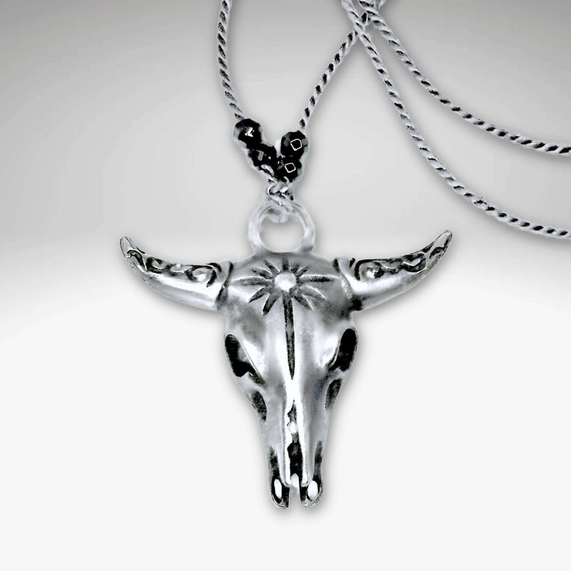 Bison Skull Necklace in matte silver finish with intricate detailing, hanging on a silk cord with hematite beads.