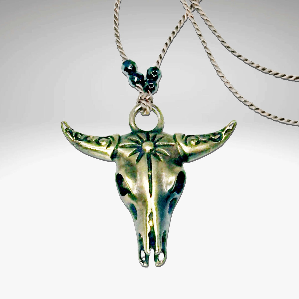 Bison Skull Necklace featuring a detailed pendant on a sleek silk cord with hematite beads, available in Matte Silver and Antique Brass.