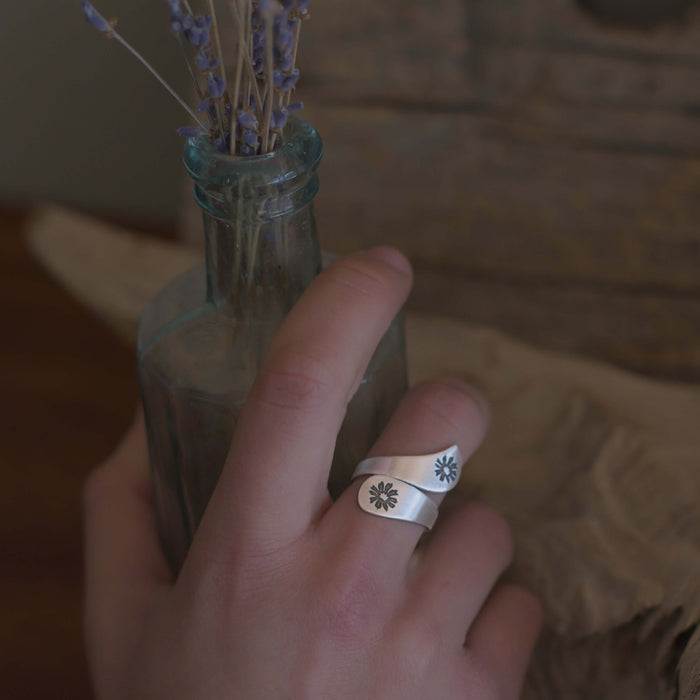 Bitterroot Bypass Adjustable Ring worn on a hand holding a vintage glass bottle with lavender.