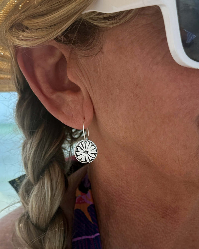 Bitterroot Flower Earrings worn by a woman with a braid, showcasing their floral design and elegant drop style.