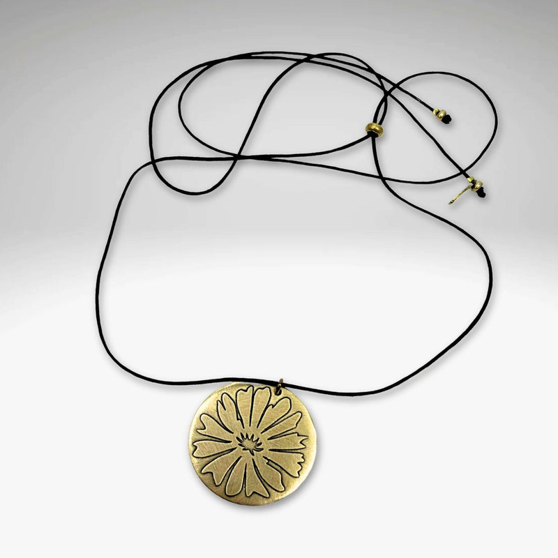 Bitterroot Necklace featuring a bold etching of the bitterroot flower in antique brass finish on a black cord.