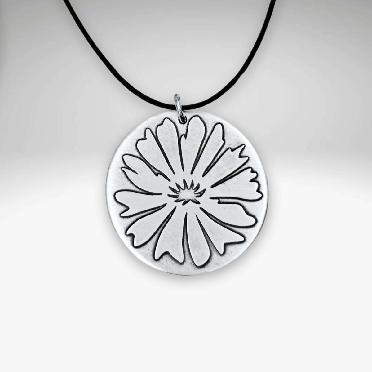 Bitterroot Necklace with fine line etching of a large bitterroot flower on a black cord.
