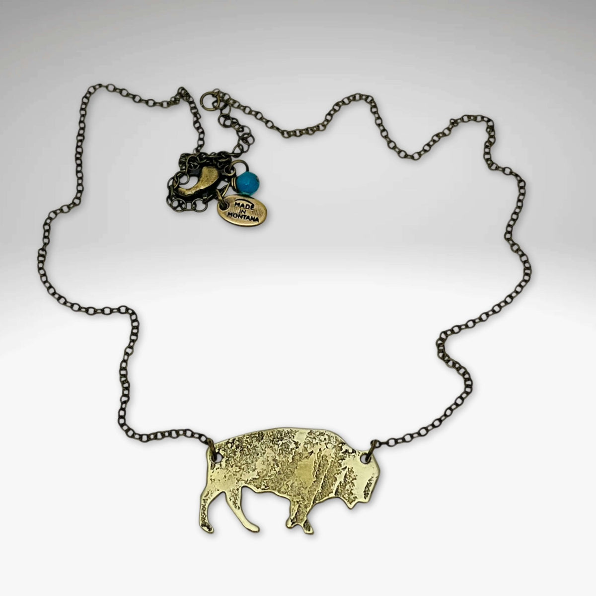 Buffalo Necklace featuring a rustic brass buffalo pendant on a cable chain, highlighting its adjustable length.