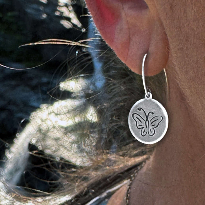 Butterfly Earrings featuring an intricately etched butterfly design in Matte Silver finish worn on a model's ear.