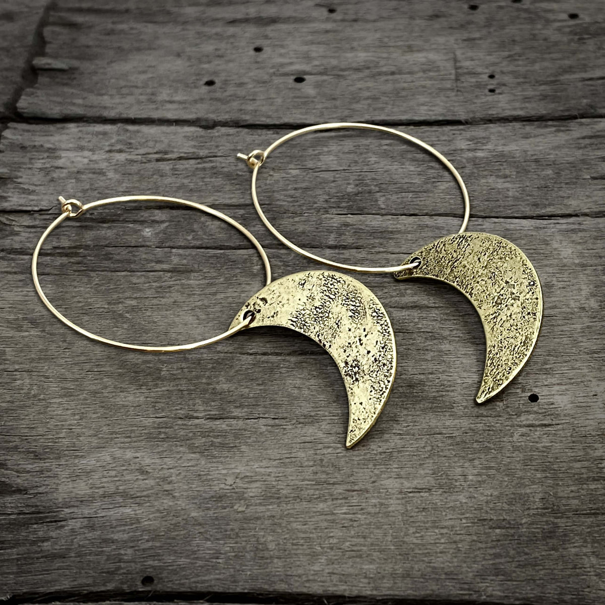 Crescent Moon Hoop Earrings on rustic wooden background, featuring hammered brass moons and gold-filled hoops.