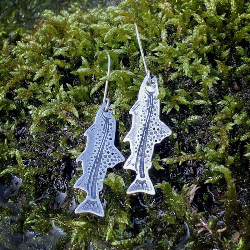 Daphne Lorna Fishing Trout Earrings – Handmade Montana Wildlife Jewelry, Matte Silver or Antique Brass on moss background.