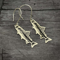 Daphne Lorna Fishing Trout Earrings – Handmade Montana Wildlife Jewelry, Matte Silver or Antique Brass on wooden background.