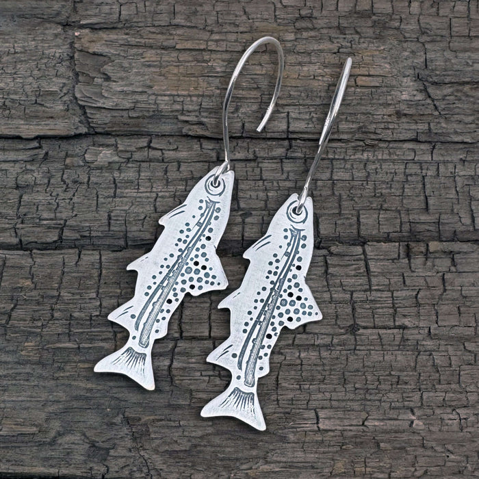 Daphne Lorna Fishing Trout Earrings – Handmade Montana Wildlife Jewelry, Matte Silver or Antique Brass on wooden background.