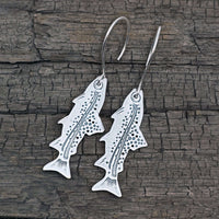 Daphne Lorna Fishing Trout Earrings – Handmade Montana Wildlife Jewelry, Matte Silver or Antique Brass on wooden background.