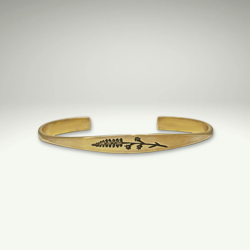 a gold bracelet with a flower design on it