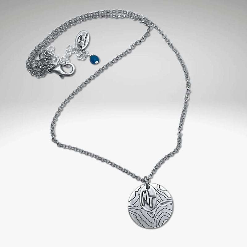 Explore MT Necklace featuring a topographic map design and MT etched on a round disk in Matte Silver.