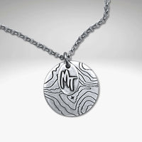 Explore MT Necklace featuring a topographic map design in Matte Silver with MT etched on a round disk.