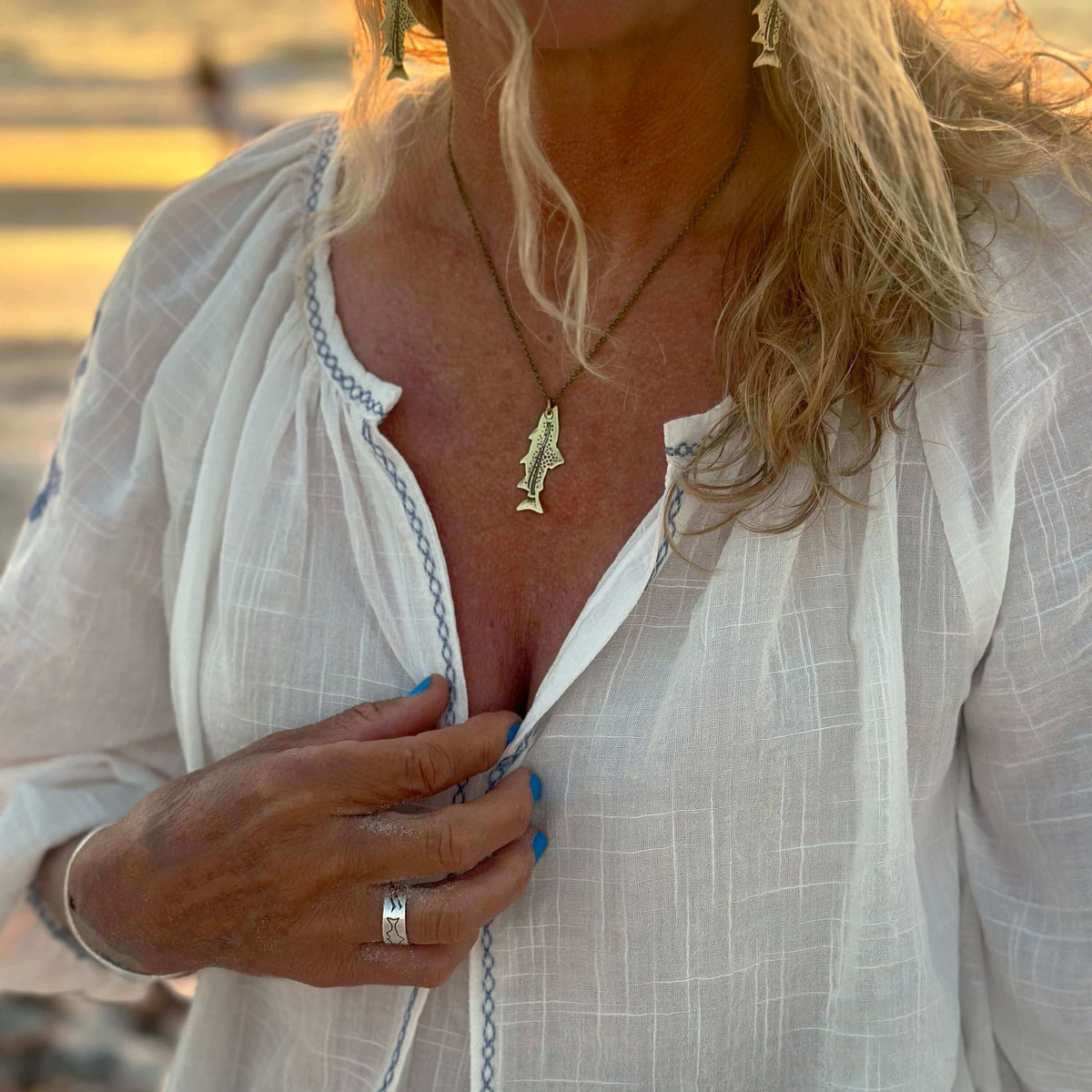 Daphne Lorna Fishing Trout Earrings – Handmade Montana Wildlife Jewelry, Matte Silver or Antique Brass worn by a woman.