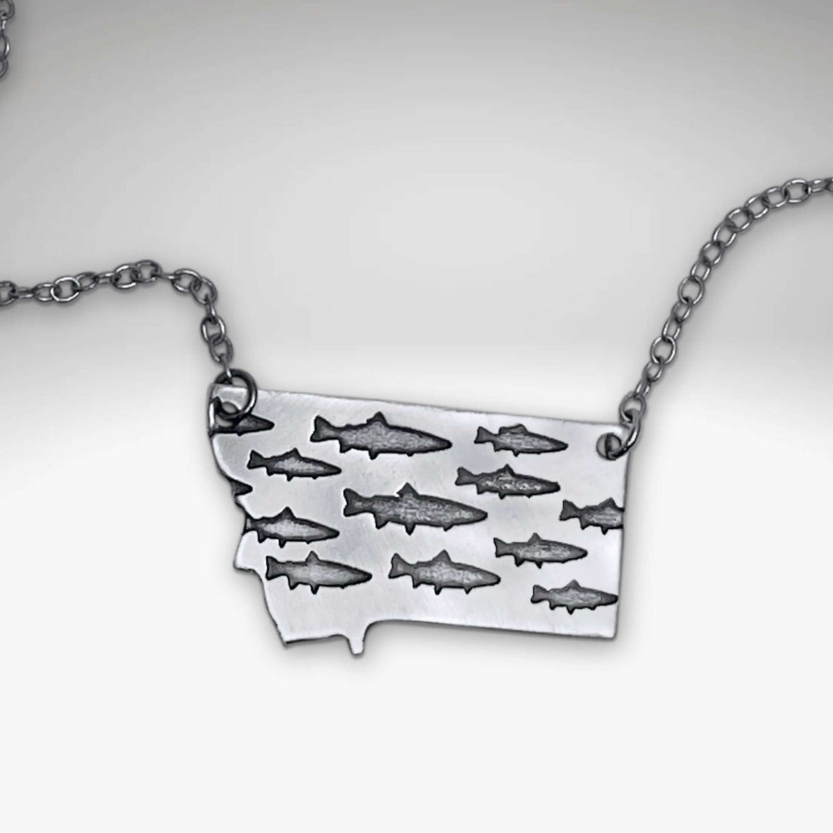 Fishing In Montana Necklace featuring intricate trout designs on a Montana state outline.