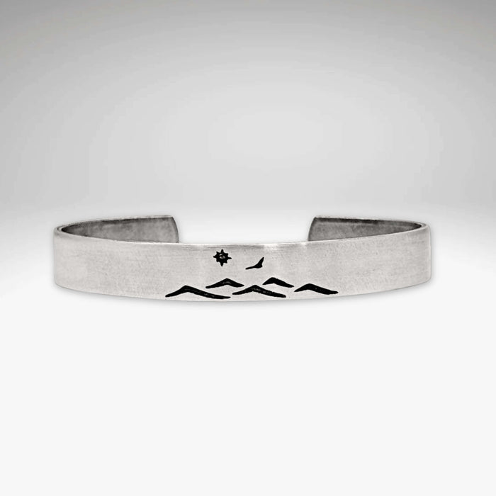Fly Over cuff bracelet featuring mountain design, bird, and sun, adjustable for men and women, showcasing nature's beauty.