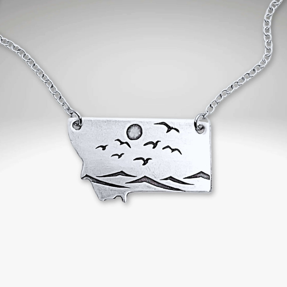 Flyover Montana - Necklace with Mountains birds and sun featuring a silver pendant showcasing nature.