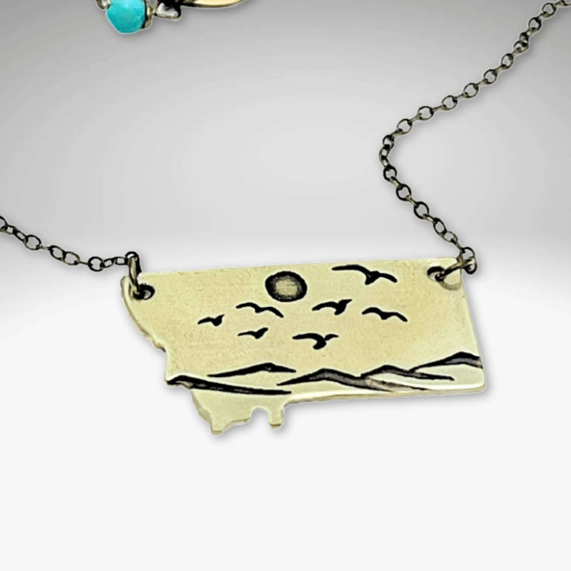 Flyover Montana - Necklace with Mountains birds and sun showcasing an engraved Montana pendant.