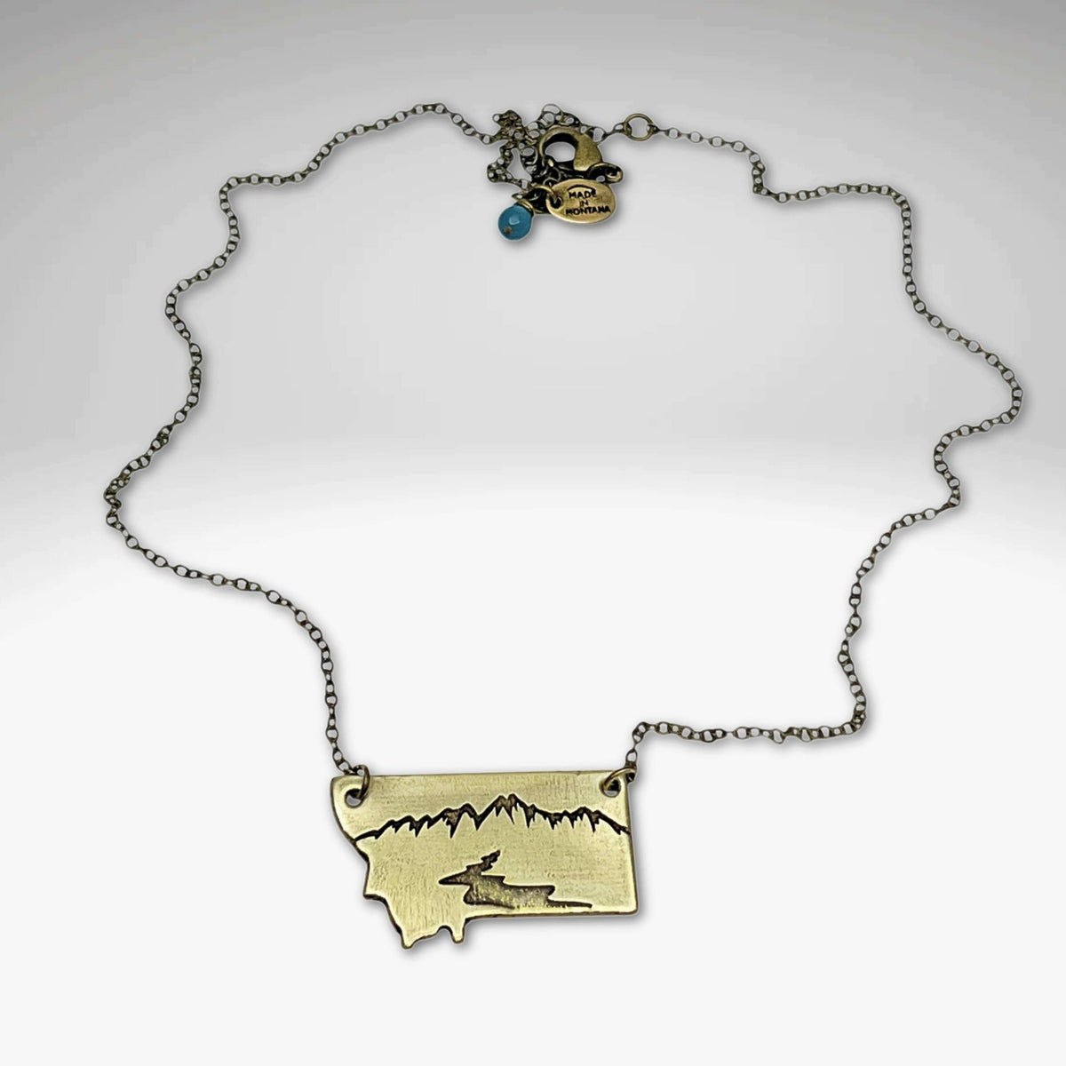 River Run Necklace featuring Montana outline, mountain peak, and winding river, perfect for nature lovers.