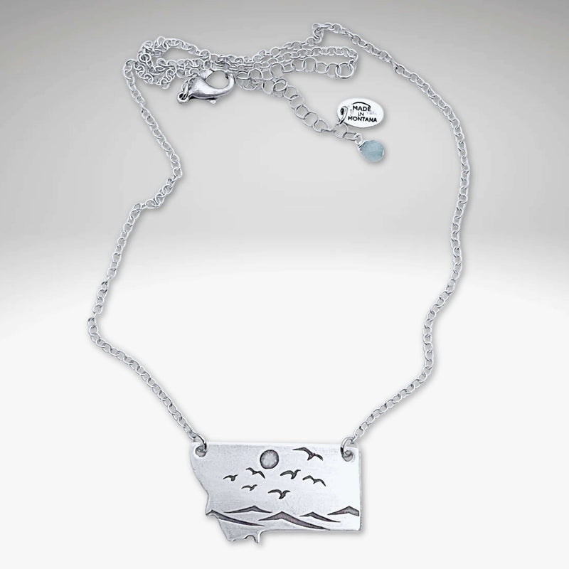 Flyover Montana - Necklace with Mountains birds and sun showcasing silver pendant of mountains, birds, and sun.