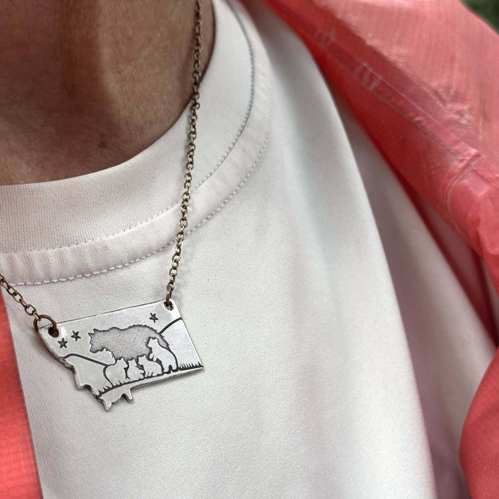 Four Cubs - Montana Bear Necklace in matte silver, showing bear design on adjustable chain worn with a white shirt.